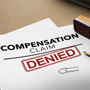 A red stamp with the word DENIED is placed over a document requesting compensation claim denied. - Leep Tescher Helfman and Zanze