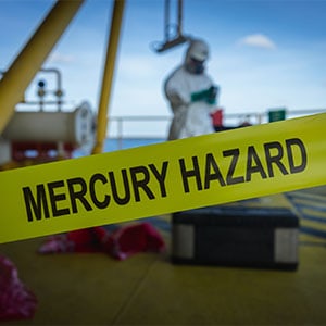 A man in a hazmat suit standing on a boat, with a warning of 'Mercury Exposure Risk' - Leep Tescher Helfman and Zanze