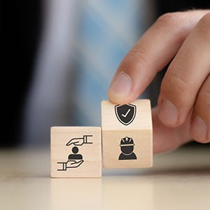 Person stacking blocks with safety icons. Building workplace safety - Leep Tescher Helfman and Zanze