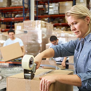 In a retail warehouse, a woman efficiently manages boxes, ensuring smooth operations. - Leep Tescher Helfman and Zanze