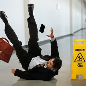 A man in a suit lying on the floor with his phone. Workplace risks in restaurants - Leep Tescher Helfman and Zanze