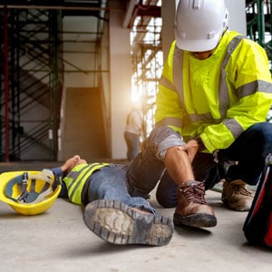 A construction worker in safety gear aiding a person on the ground - Leep Tescher Helfman and Zanze
