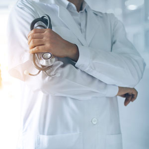 Doctor standing in a white coat, holding a stethoscope - Leep Tescher Helfman and Zanze.